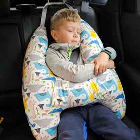 Ein Kind, das friedlich im Autositz schläft, gestützt durch ein Nackenkissen mit einem fröhlichen Wal- und Meerestier-Design, eine Szene, die Sicherheit und Komfort während der Autofahrt betont.